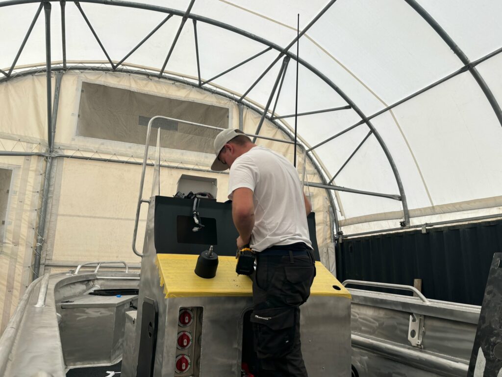 Technicien Nautique Services au montage de l’électronique d’une console à l’atelier